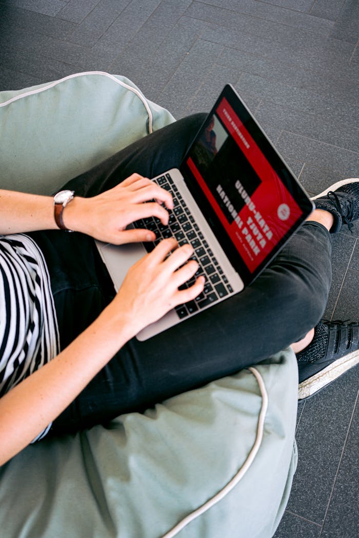 our-services-3 Person working remotely on a laptop while sitting comfortably on a beanbag chair indoors.