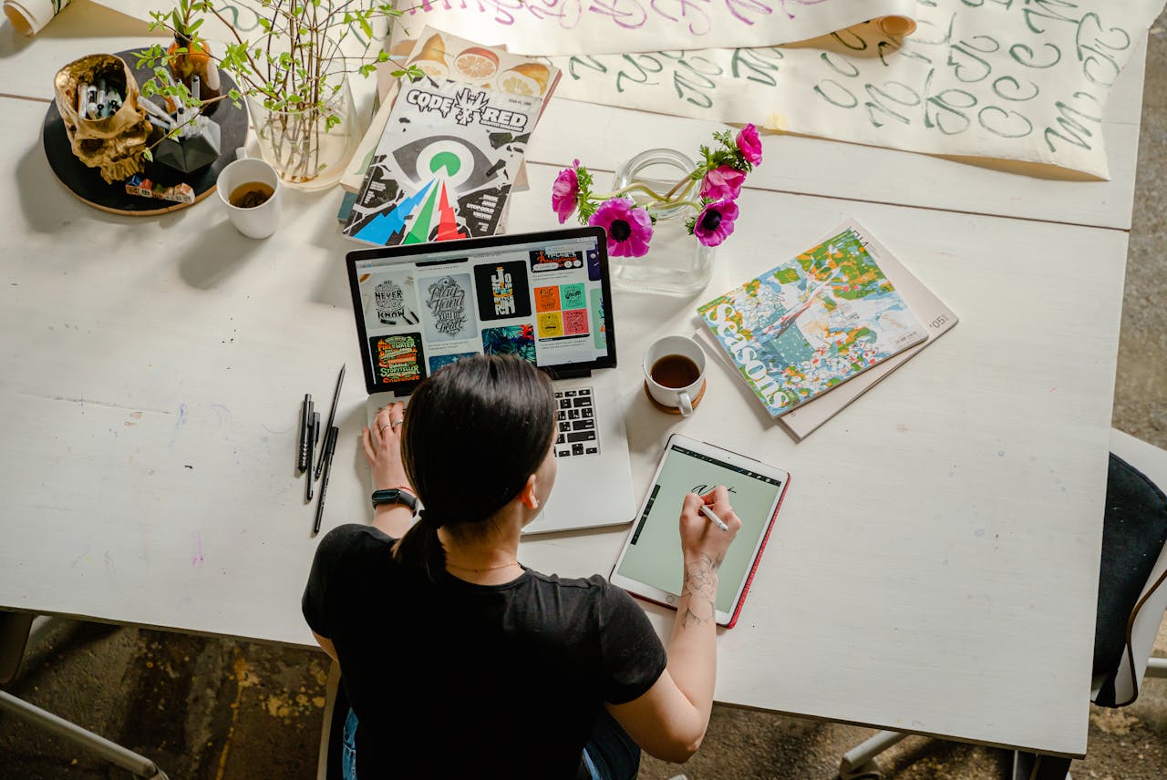 why-choose-us Artistic workspace featuring calligraphy and digital design on a tablet and laptop.